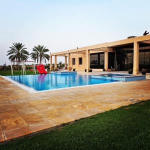 a swimming pool with a red slide in front of a building at مزرعة الاسترخاء in Umm Al Quwain