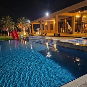 a swimming pool in front of a house at night at مزرعة الاسترخاء in Umm Al Quwain
