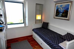 a small bedroom with a bed and two windows at Isabella in Silba