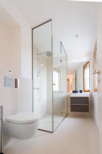 uma casa de banho branca com uma banheira e uma cabina de duche em vidro. em Seehaus SeeZeit - Am Hafen em Neusiedl am See