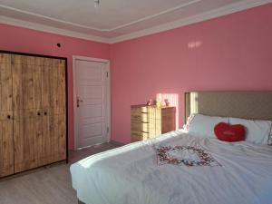 a bedroom with pink walls and a bed with a heart pillow at Yılmaz Villa in Macka