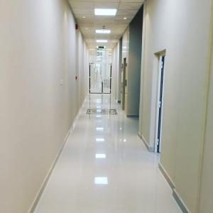 an empty hallway in a building with white floors at Argaan Apartment in Salalah