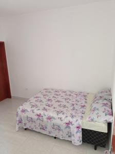 a bed in a room with a white wall at Casa de praia Melo in Itanhaém +8 photos