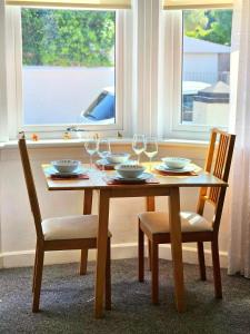 a wooden table with two chairs and wine glasses at Parkside 2 bedrooms appartment with encolsed garden in Largs
