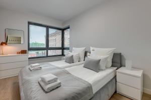 a white bedroom with a large bed with towels on it at Downtown Aparments City Center SCALA Apartments & Parking in Gdańsk