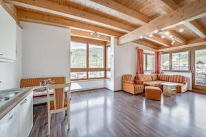 cocina abierta y sala de estar con techos de madera. en Ferienhaus Platöll, en Serfaus