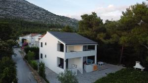 a white house with a solar roof on a hill at Apartmani Kim in Starigrad