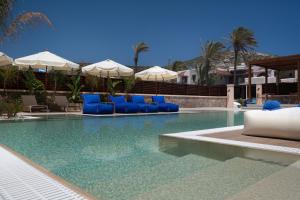 a swimming pool with blue lounge chairs and umbrellas at Prasonisi Light House Boutique Hotel in Prasonisi