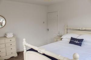 een slaapkamer met een wit bed en een blauw kussen bij Lovely Bungalow Close to Beach in Prestatyn