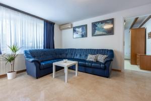 uma sala de estar com um sofá azul e uma mesa em Amarie em Dramalj