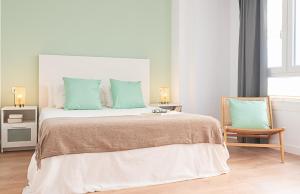 een slaapkamer met een groot bed met groene kussens en een stoel bij SlowHome Catedral in Almería