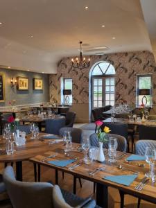 un ristorante con tavoli e sedie in legno e un lampadario a braccio di White Horse Inn & Restaurant a Stoke Albany