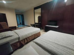 a hotel room with two beds and a desk at Hotel Syariah Taman Cibinong 2 By FPH 