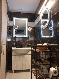 a black tiled bathroom with a sink and a mirror at Arcade City Apartment in Rethymno +28 photos