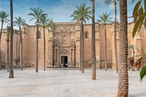 a building with palm trees in front of it at SlowHome Catedral in Almería