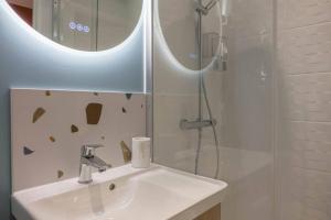 La salle de bains est pourvue d'un lavabo et d'une douche avec un miroir. dans l'établissement Bel appartement idéalement situé, à Orléans
