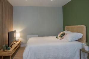 - une chambre avec un lit blanc et une télévision dans l'établissement Bel appartement idéalement situé, à Orléans