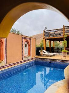 a swimming pool with a patio and a house at Dar Rihana Dadès in Aït Idaïr