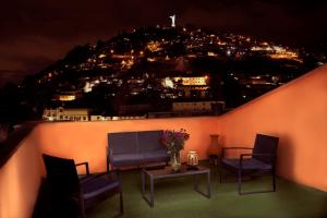 balkon z 2 krzesłami, kanapą i stołem w obiekcie La Posada Colonial w mieście Quito