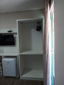 a closet with white shelves and a television in a room at Pousada Serrano in Campos do Jordão