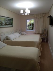 a bedroom with two beds and a window at Pousada Serrano in Campos do Jordão