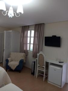 a bedroom with a bed and a chair and a television at Pousada Serrano in Campos do Jordão