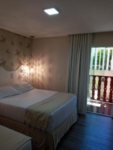 Cette chambre comprend 2 lits et une fenêtre. dans l'établissement Pousada Serrano, à Campos do Jordão