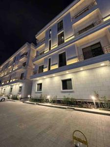 un gran edificio blanco con un estacionamiento delante de él en New apartment, two entrances en Riad