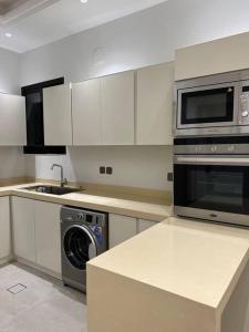 La cocina está equipada con microondas y lavavajillas. en New apartment, two entrances, en Riad