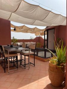 eine Terrasse mit einem Tisch, Stühlen und einem Sonnenschirm in der Unterkunft Dar Randigaba in Taroudant