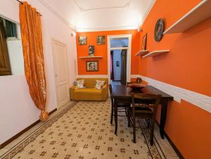 uma sala de jantar com paredes cor de laranja e uma mesa e cadeiras em Il Cortile Siciliano Apartments em Trapani