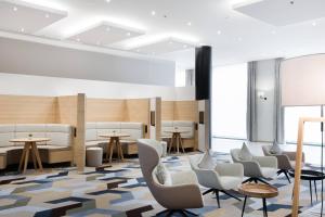 a waiting room with chairs and tables and windows at Courtyard By Marriott Brussels in Brussels