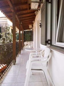 una fila de mesas y sillas blancas en un porche en Pension Nikolas, en Skiathos