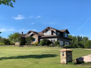 a large black house on a green lawn at Dragonfly Inn Walkout Suites in Sherwood Park