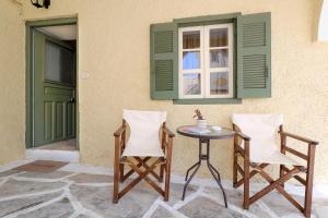two chairs and a table in front of a building at Feidiou 1, vol I in Egina