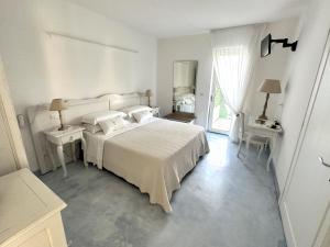 una camera bianca con un grande letto e una finestra di Adagio Salentino a Porto Cesareo