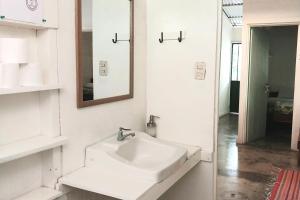 Baño blanco con lavabo y espejo en Bajo el Arbol B&B en Santa Teresa