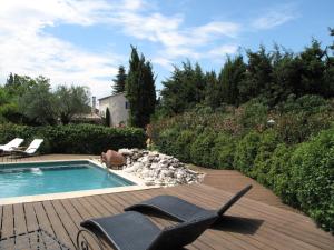 una piscina con una silla y un perro de pie junto a ella en Mirabelle en Provence, en Eygalières
