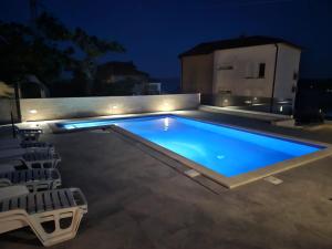 uma piscina à noite com cadeiras à volta em Apartment Ankica em Crikvenica