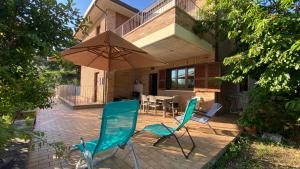 een patio met 2 stoelen en een parasol bij La Casa delle Ciliegie in Assisi