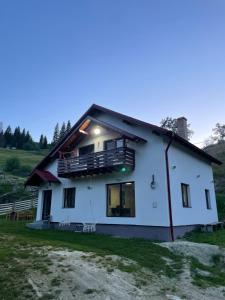 a white house with a balcony on top of it at Cabana Stânceni in Drăgoiasa