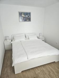 a white bedroom with a white bed and two night stands at Apartment Ankica in Crikvenica