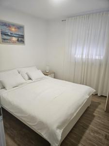 a white bed in a bedroom with a window at Apartment Ankica in Crikvenica