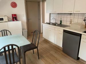 a kitchen with white cabinets and a table with chairs at Chouette appartement 5 personnes in De Haan