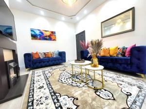 a living room with blue couches and a table at Spacious Six Bedrooms House By Sensational Stay Short Lets & Serviced Accommodation With 13 Beds, Free Parking, Free Wi-fi & Balcony in London