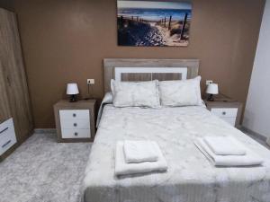 sypialnia z dużym białym łóżkiem z 2 stolikami nocnymi w obiekcie DE Apartamentos Pampin Ponte do Porto w mieście A Coruña