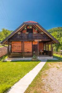 a large wooden cabin with a porch on a grass field at Brvnara Sofiana in Bajina Bašta