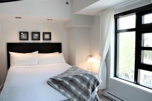 ein Schlafzimmer mit einem weißen Bett und einem Fenster in der Unterkunft 1BR Resort View at the base of Whistler in Whistler