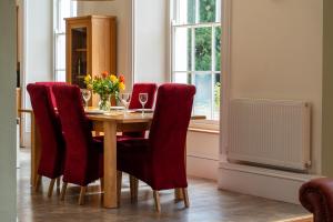 een eettafel met rode stoelen en een vaas met bloemen bij Holyland House - Greenacres Estates in Pembrokeshire