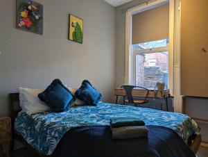 a bedroom with a bed with blue pillows and a window at Entire Apartment Near Newcastle City Centre, West Jesmond. in Town Moor
